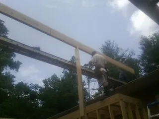 Carpenter setting a ridge beam over a new addition frame — Ice Dam Removal by Roofing Brothers in Peru